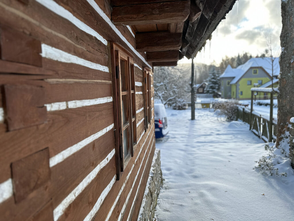 Detail střechy se sněhem a sousední chalupy